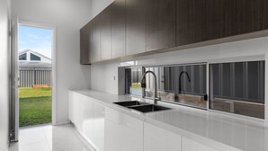 A modern kitchen with a large window, white cabinetry, and a stainless steel sink. - Cork & Vine on Coolalta  - A Cellar Door Escape (Nulkaba)