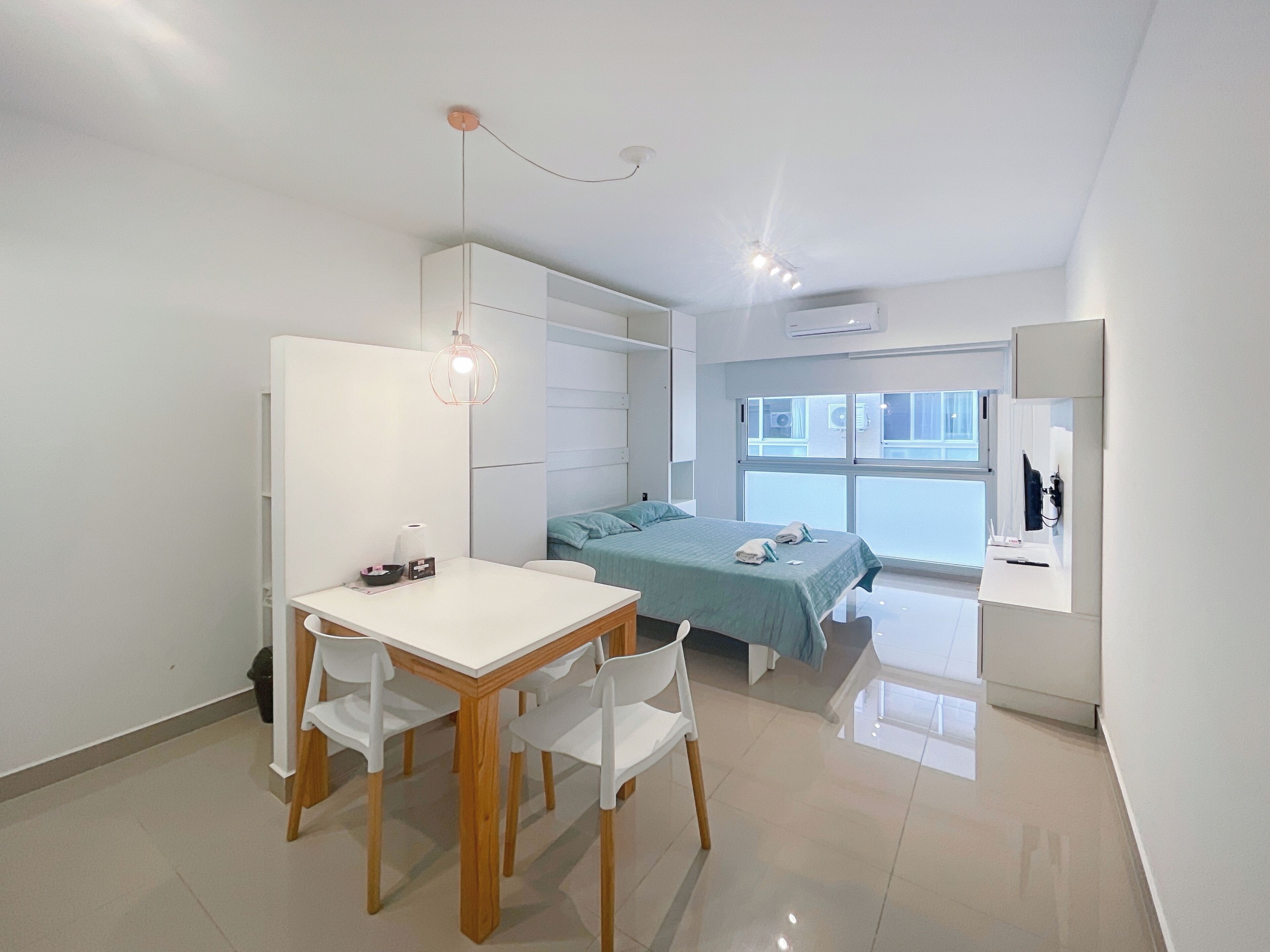 A modern bedroom with a bed, bedside table, and a desk with chairs.