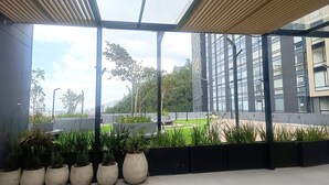 A modern building with a glass facade, outdoor seating area, and potted plants. - Loft con Tecn- Alexa (Bogotá)