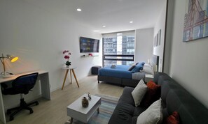 A modern hotel room with a bed, a desk, a chair, a small table, and a couch. - Loft con Tecn- Alexa (Bogotá)