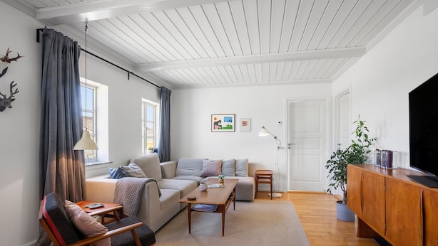 Una sala de estar moderna con sofá, sillón, mesa de centro y mueble para televisión.