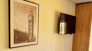 A modern living room with a framed picture of London, a flat-screen TV mounted on the wall, and a dark-colored sofa with cushions. - The best apartment in the best area of Bogota (Bogotá)