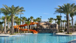 Une piscine avec un toboggan et des palmiers.
