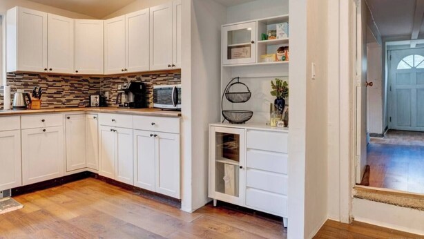 A modern kitchen with white cabinetry, a stone backsplash, and a built-in oven.