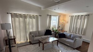 A living room with two sofas, a coffee table, a lamp, and a window with curtains.