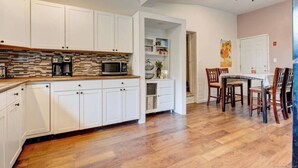 A modern kitchen with white cabinets, a wooden countertop, and a built-in microwave.