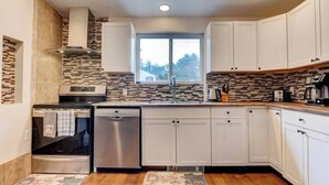 A modern kitchen with white cabinets, a stainless steel dishwasher, and a tiled backsplash.