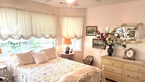 A bedroom with a bed, dresser, chair, and a window with curtains. - Charming 2BR Cottage on The Point (Colonial Beach)