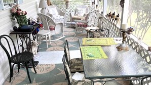 A covered porch with wicker furniture, a glass table, and decorative items. - Charming 2BR Cottage on The Point (Colonial Beach)