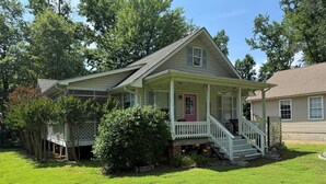 A single-story house with a front porch, a red door, and a small front yard. - Charming 2BR Cottage on The Point (Colonial Beach)
