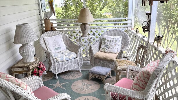 A covered porch with wicker furniture, a lamp, and a bird feeder. - Charming 2BR Cottage on The Point (Colonial Beach)