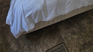 Un dormitorio con una cama grande, un ventilador de techo y una ventana con cortinas.
