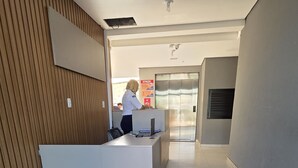 Un área de recepción con un mostrador, un cartel que dice "Villas do Porto RESIDENCE" y un ascensor al fondo.