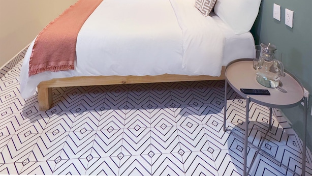 A bedroom with a bed, a bedside table with a lamp, a ceiling fan, a TV mounted on the wall, and a window with a blue pattern. - Private room with private bathroom in the Americana neighborhood (Guadalajara)