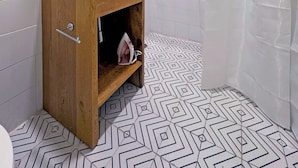 A bathroom with a wooden vanity, a white sink, a towel rack, a shower curtain, and patterned floor tiles. - Private room with private bathroom in the Americana neighborhood (Guadalajara)