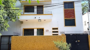 A modern two-story building with a brick facade, multiple windows, and a gated entrance. - Private room with private bathroom in the Americana neighborhood (Guadalajara)