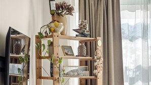 Ein gemütliches Wohnzimmer mit einem Holzregal, einer Topfpflanze und einem bequemen Sofa.