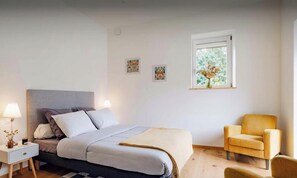 A bedroom with a bed, bedside tables, a window with a view, and a chair.