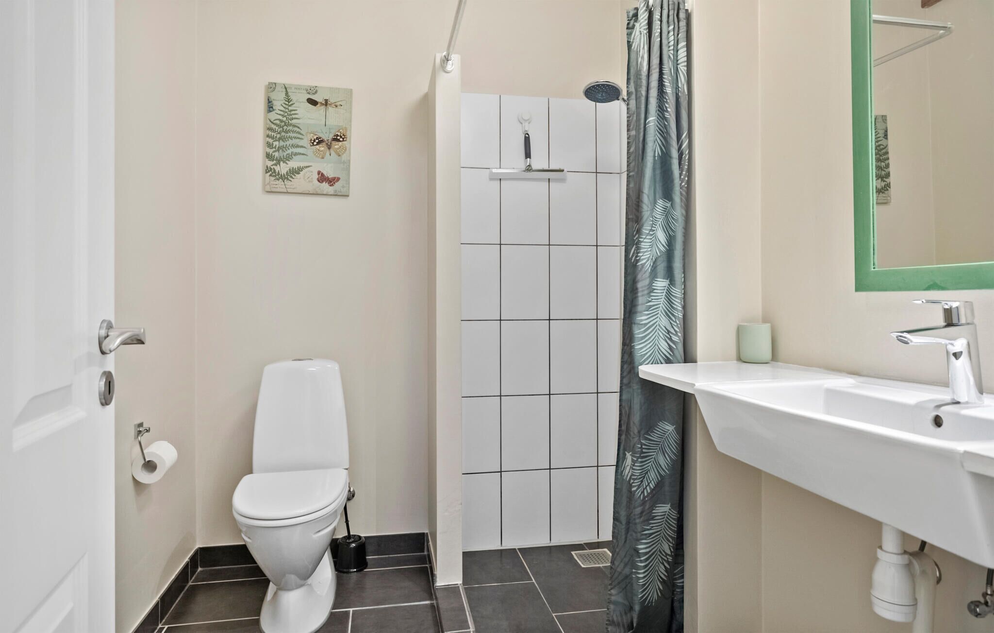 A bathroom with a toilet, shower, and sink.