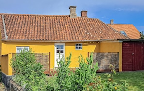 A yellow building with a tiled roof, a white door, and a red garage door.