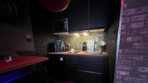 A compact kitchen with a microwave, coffee maker, and sink.