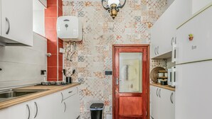 Eine schmale Küche mit weißen Schränken, einer Holz Arbeitsplatte, einem Edelstahl-Spülbecken, einem Gasherd und einer gemusterten Spritzschutzeinrichtung.