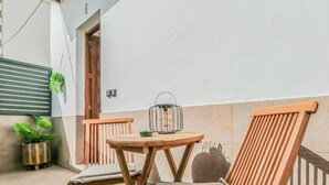 Ein kleiner Außenbereich mit einem runden Holztisch und zwei Holzstühlen mit Kissen.