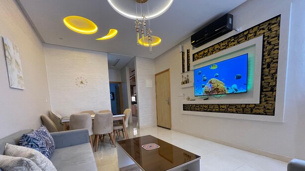 A modern living room with a sofa, coffee table, and a TV mounted on a stone wall.