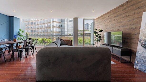 Ein modernes Wohnzimmer mit großem Fenster, einer Couch, einem Essbereich und einem Fernseher.