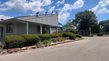 A building with a covered porch, a sign reading "Lobby," and a parking lot.