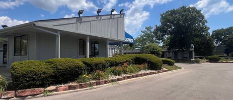 A building with a covered porch, a sign reading "Lobby," and a parking lot.