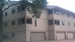 A two-story building with a flat roof, multiple windows, and two garages. - Tomar Park Apt 8 - KP101APT8 (Sioux Falls)
