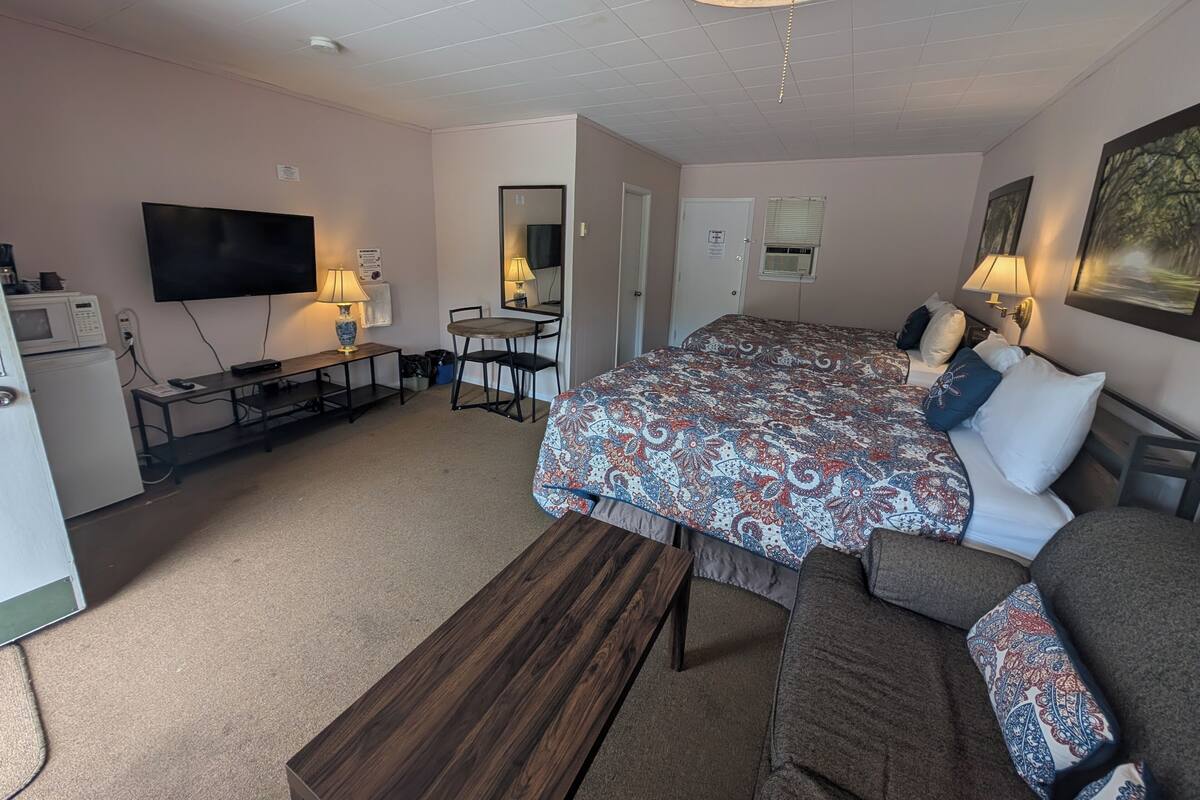 A hotel room with a large bed, a desk with a computer, a TV, and a microwave.