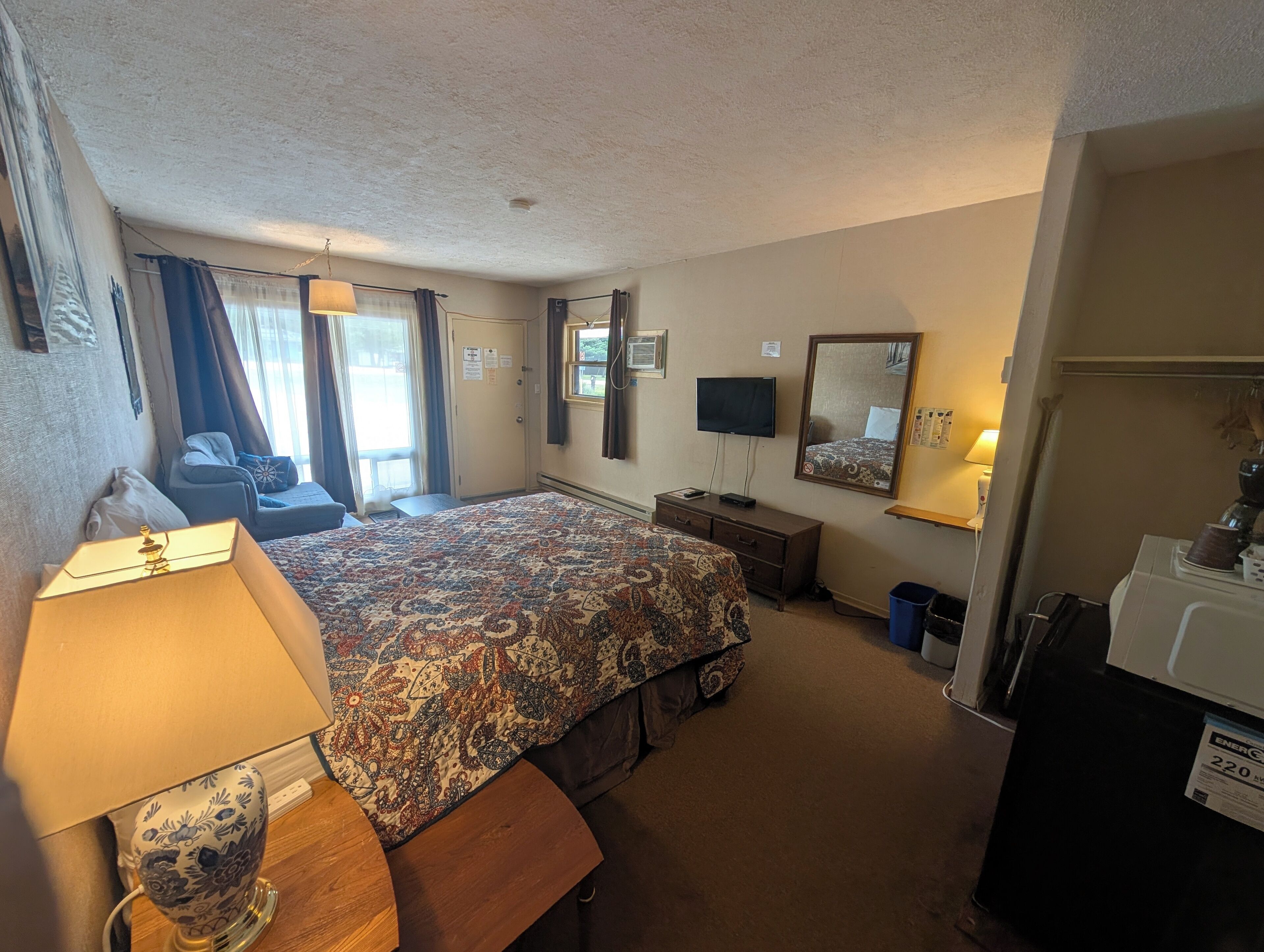 Une chambre d’hôtel avec un grand lit, un bureau, une télévision, un miroir et une machine à café.