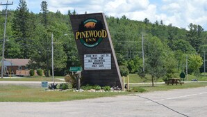 A Pinewood Inn sign with amenities like free WiFi, Sat TV, and essential workers' gratitude. - PINEWOOD INN (Barry's Bay)