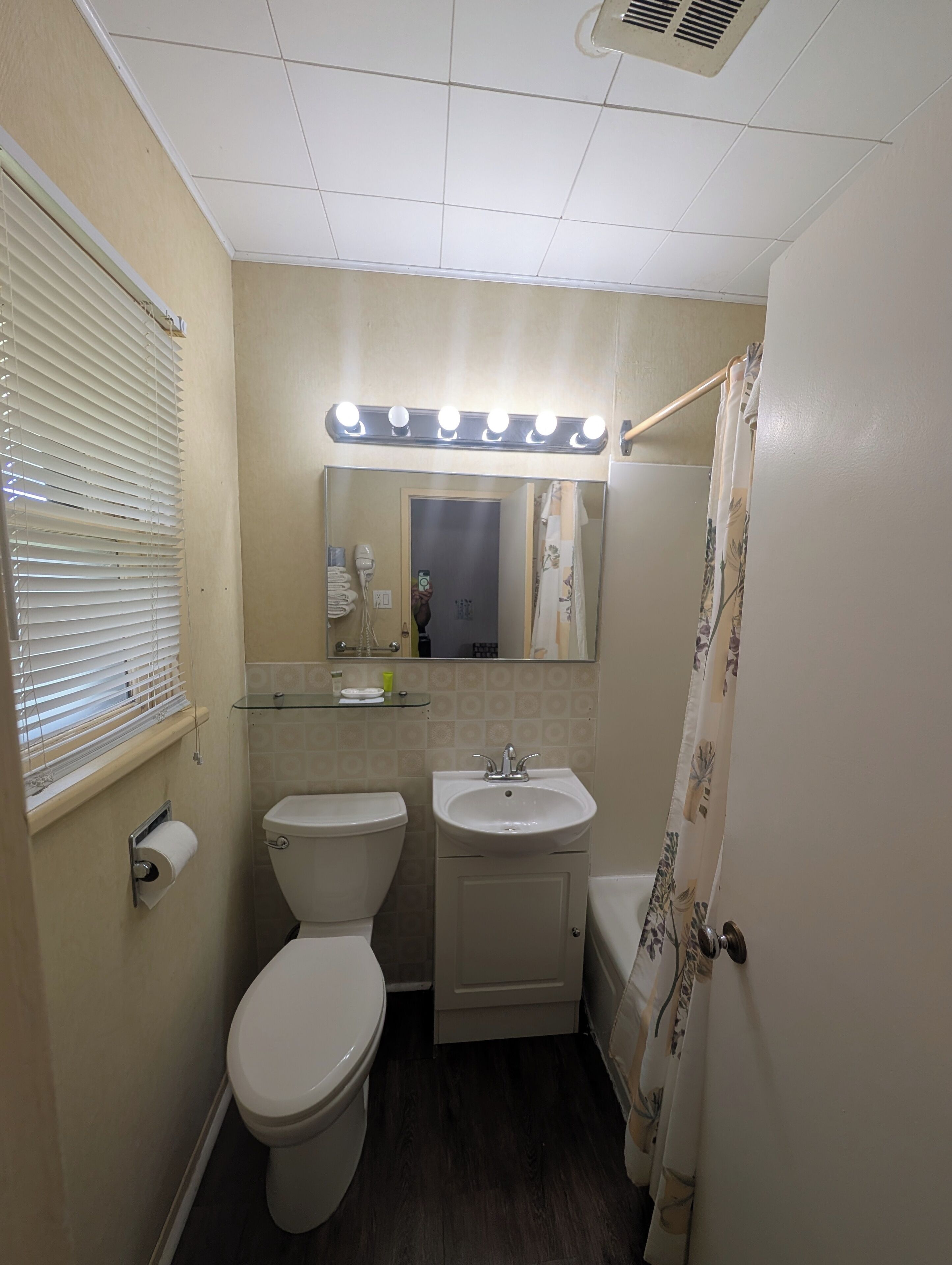 Une salle de bain équipée de toilettes, d’un lavabo et d’un miroir de coiffeuse avec éclairage.