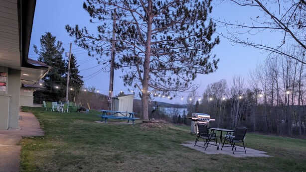 A backyard with a picnic table, grill, and outdoor seating area. - PINEWOOD INN (Barry's Bay)
