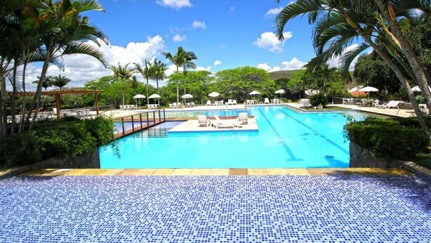 A large outdoor swimming pool surrounded by palm trees and lounge chairs. - Hotel Fazenda Portal de Gravatá (Gravatá)