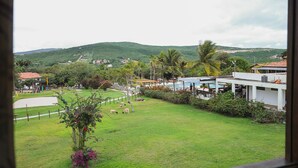 A view of a grassy area with a pool and buildings in the background. - Hotel Fazenda Portal de Gravatá (Gravatá)