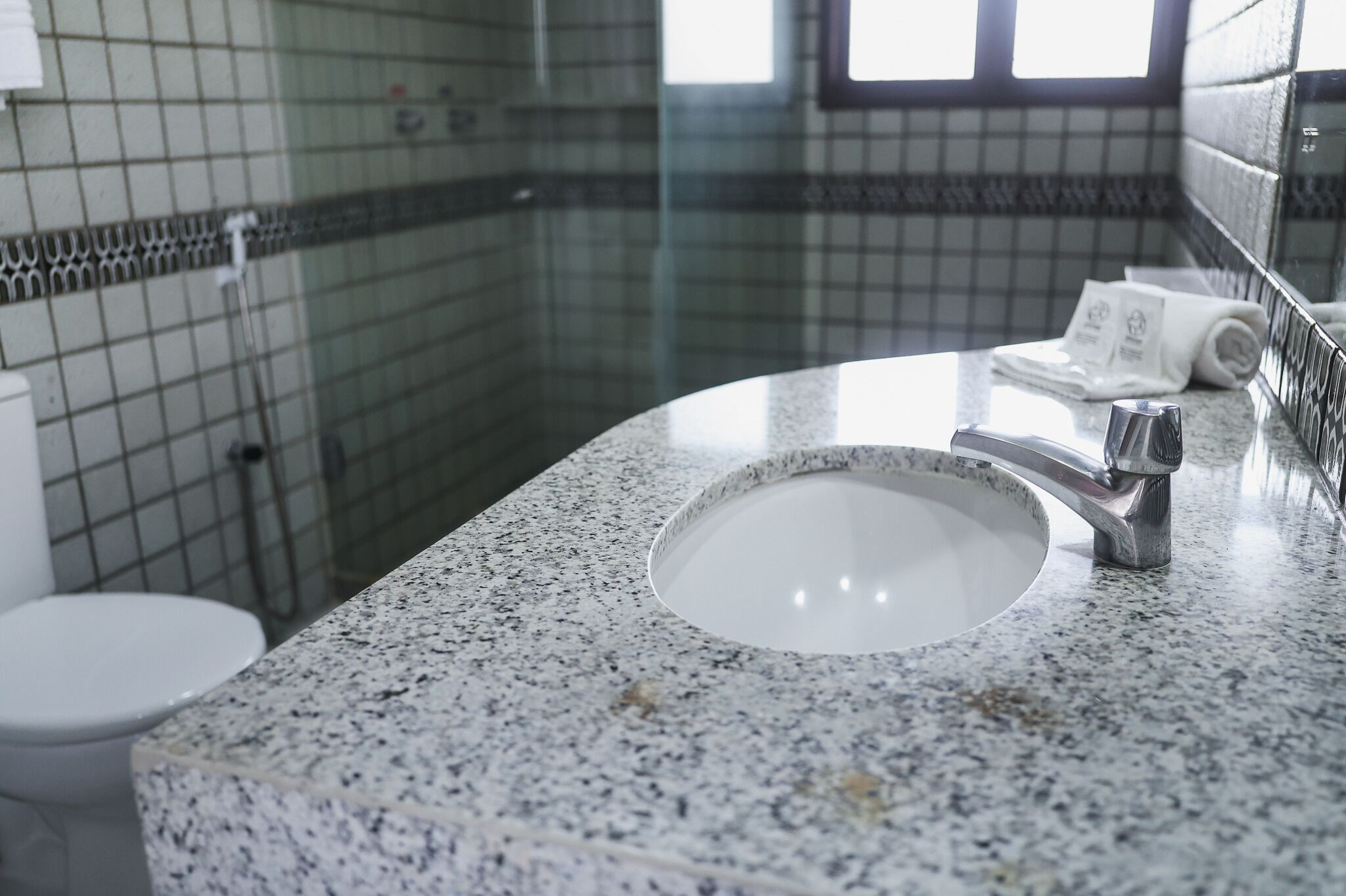 Un baño con encimera de granito, lavabo blanco y espejo.