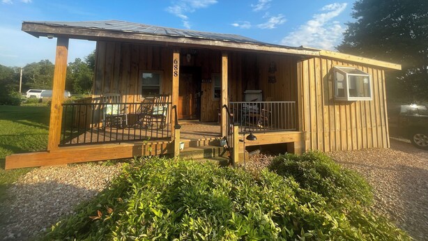 Une cabane en bois avec une véranda, une petite fenêtre et le numéro « 688 » sur la porte.