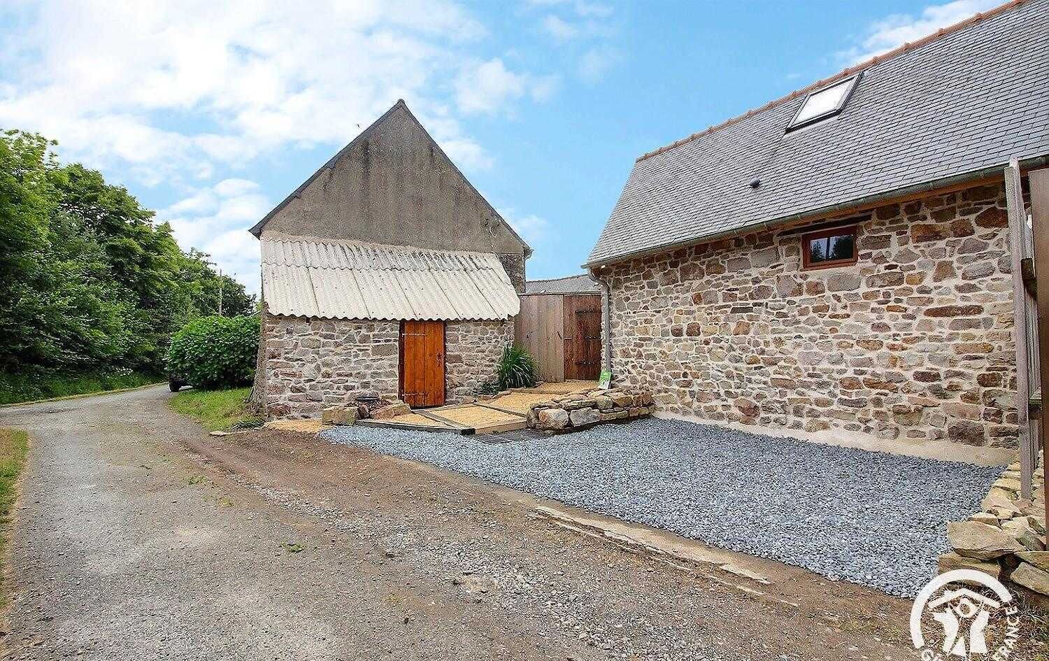 Un edificio in pietra con una porta in legno e un vialetto sterrato.