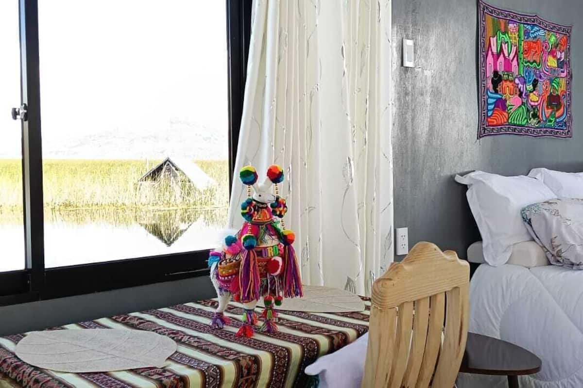 Une chambre à coucher avec un lit, une chaise en bois, une petite table et une statue colorée.