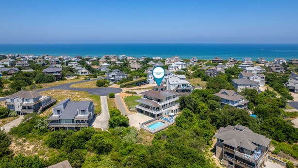 An aerial view of a coastal residential area with houses, a swimming pool, and a prominent blue location marker. - Point of View: Saltwater Pool, Hot Tub, Amazing Ocean and Sound Views (Duck)
