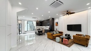 Una sala de estar moderna con piso de mármol, dos sofás, una mesa de centro y un televisor montado en la pared.