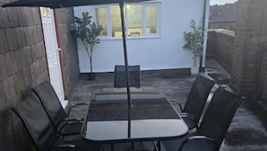 A patio with a table and chairs, a black umbrella, and potted plants. - 2 Bed - Sleeps 6 - Private Balcony - City Centre (Wolverhampton)