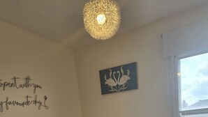 A bedroom with a tufted headboard, a bed with pink and gray bedding, a decorative wall piece, and a window with blinds. - 2 Bed - Sleeps 6 - Private Balcony - City Centre (Wolverhampton)
