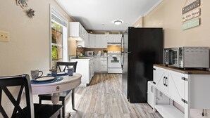 A compact kitchen with white cabinets, a black refrigerator, and a microwave on a wooden countertop. - Charming Guest House – 1BR + Sleeping Nook, Full Kitchen, Gazebo, & Boat Parking (Marshall)