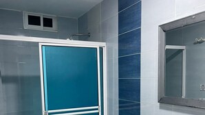 A bathroom with a white toilet, a sink, and a shower stall with a blue door. - Apartment 201 (San Andrés Islas)