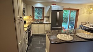 A modern kitchen with a central island, stainless steel appliances, and a view of the outdoors.